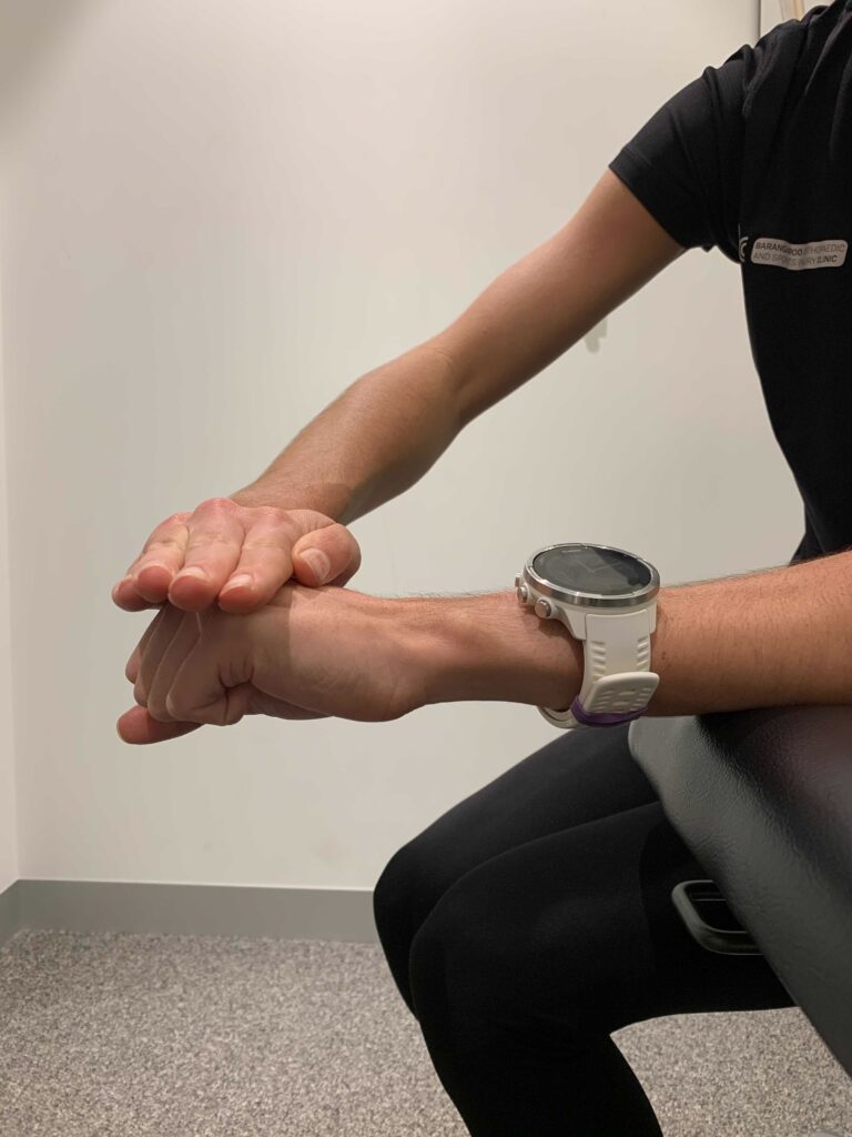 Woman demonstrates an isometric wrist extension to treat tennis elbow